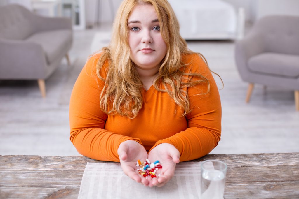 tučná žena držiaca lieky v rukách