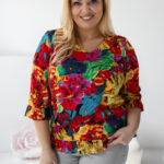 Letný farebný top z viskózy s výstrihom do V a volánikmi, trojštvrťové rukávy, modelka v šedých nohaviciach