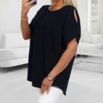 Žena v čiernom tričku s výrezmi na ramenách a bielych nohaviciach, fotí sa v zrkadle