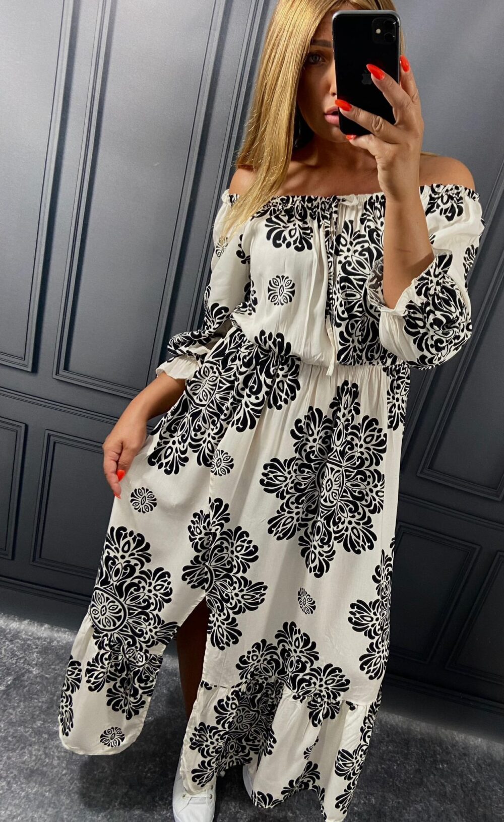 Žena v dlhých viskózových šatách s čierno-bielym ornamentálnym vzorom fotí outfit v zrkadle