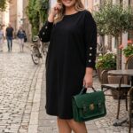 Čierne plus size šaty s lodičkovým výstrihom, trojštvrťovými rukávmi a zlatými kovovými očkami na rukávoch