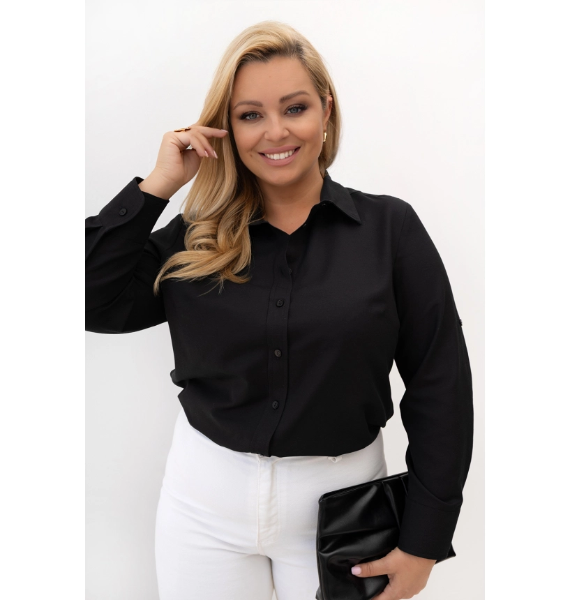 Plus size žena v čiernej bavlnenej blúzke s dlhými vyhrňovacími rukávmi a zapínaním na gombíky.