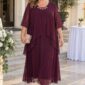 Plus size spoločenské šaty v baklažánovej farbe so splývavou šifónovou vrstvou, 3/4 rukávmi a ozdobou pri výstrihu.
