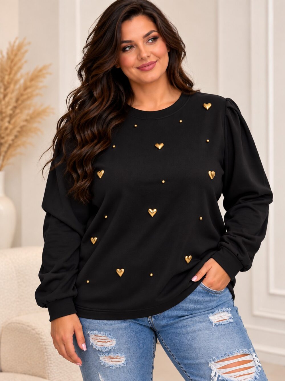 Čierna dámska plus size mikina so zlatými plastickými srdiečkami a drobnými zlatými ozdobami, okrúhlym výstrihom a dlhými nazberanými rukávmi. Modelka ju kombinuje so svetlomodrými roztrhanými rifľami.