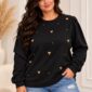 Čierna dámska plus size mikina so zlatými plastickými srdiečkami a drobnými zlatými ozdobami, okrúhlym výstrihom a dlhými nazberanými rukávmi. Modelka ju kombinuje so svetlomodrými roztrhanými rifľami.