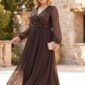 Plus size modelka v dlhých čokoládovohnedých spoločenských šatách s flitrovým zdobením na živôtiku, prekladaným výstrihom, priehľadnými šifónovými rukávmi a splývavou sukňou. Outfit dopĺňajú bordové semišové lodičky a malá kabelka v champagne odtieni.
