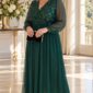 Plus size modelka v dlhých smaragdovozelených šatách s flitrovým zdobením na živôtiku, prekladaným výstrihom, priehľadnými šifónovými rukávmi a splývavou sukňou. Outfit dopĺňajú zlaté lodičky a čierna listová kabelka.