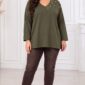 Plus size modelka v kaki tunike s V-výstrihom a perlovým zdobením na jednom ramene, skombinovanej s hnedými úzkymi nohavicami a béžovými členkovými topánkami na podpätku. Voľný strih tuniky siaha pod boky.
