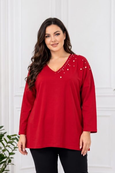 Detail červenej plus size tuniky s voľným strihom, dlhými rukávmi a V-výstrihom. Biele perly rôznych veľkostí zdobia asymetricky jednu stranu výstrihu, rameno a hornú časť tuniky.