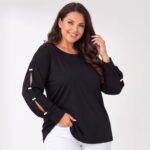 Čierna dámska plus size tunika s okrúhlym výstrihom a dlhými rukávmi s rozparkami zdobenými bielymi perlami. Detail tuniky na modelke v bielych nohaviciach.