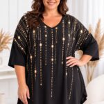 Plus size modelka v čiernej oversize tunike s výstrihom do V a zlatistou potlačou padajúcich retiazok a kryštálikov. Tunika má voľné rukávy a dĺžku 82 cm.