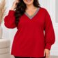 Plus size modelka v červenej tunike s voľným strihom, striebristosivým lemovaním V-výstrihu a dlhými balónovými rukávmi zakončenými manžetami. Tuniku dopĺňajú čierne nohavice. Modelka stojí vo svetlom elegantnom interiéri.