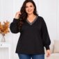 Plus size modelka v čiernej tunike s trblietavým strieborno-sivým V-výstrihom, balónovými rukávmi a širokými manžetami. Tuniku kombinuje s modrými rifľami.